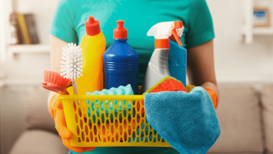 Woman in green shirt gholding basket of cleaning products